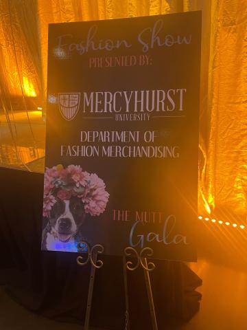Mutt Gala poster at an event, hosted in a dark room with orange lights
