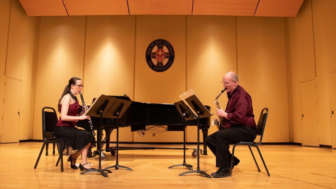 female and male professors play saxophones on stage