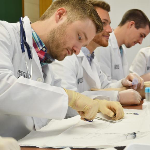 three male physician assistant students work in a lab