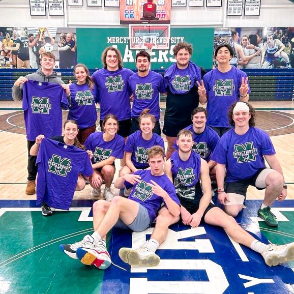 a team of students pose on the mercyhurst basketball court