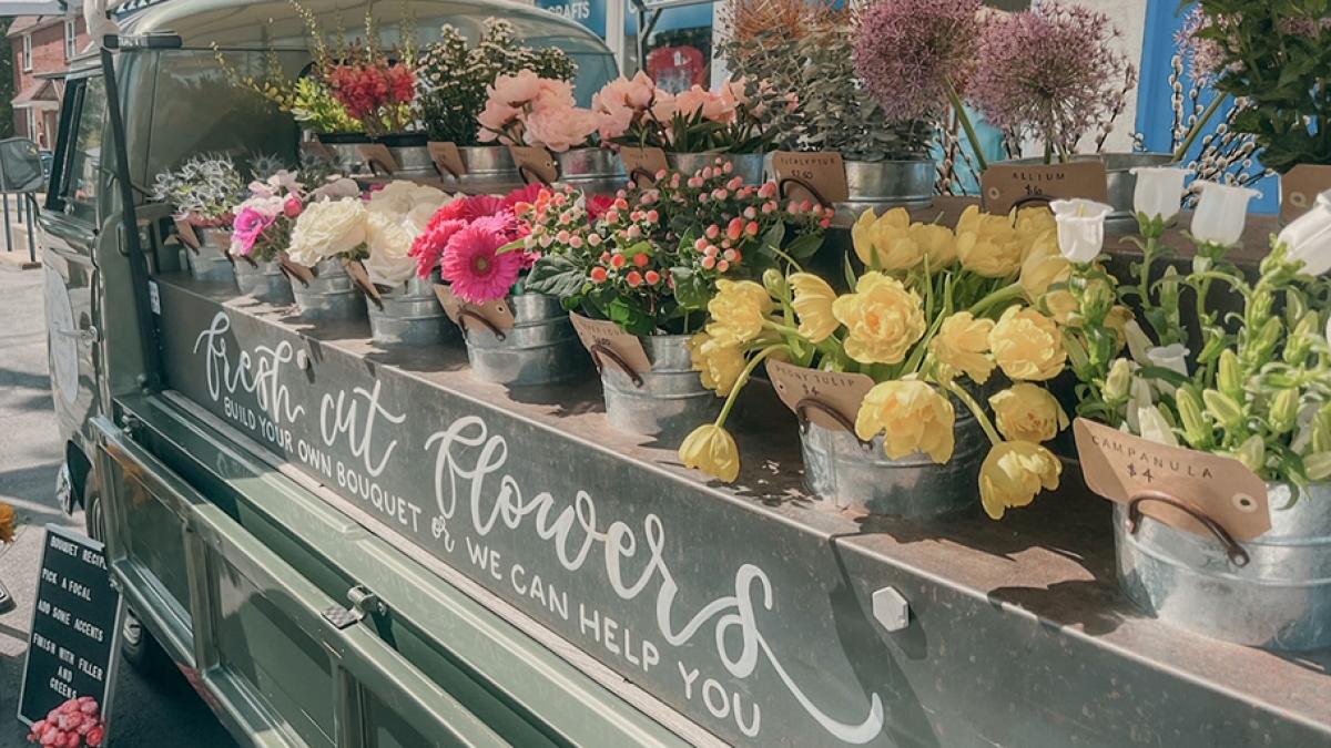 Green flower truck with buckets of flowers in the truck bed