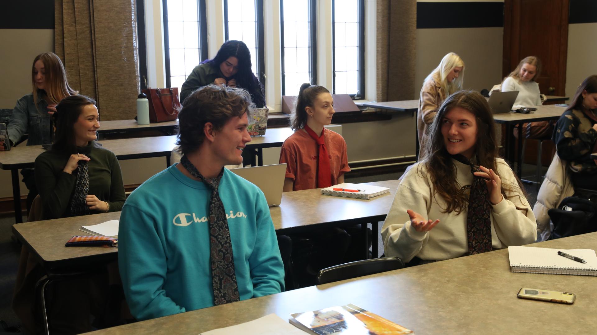 a male and female student practice tying ties in a classroom