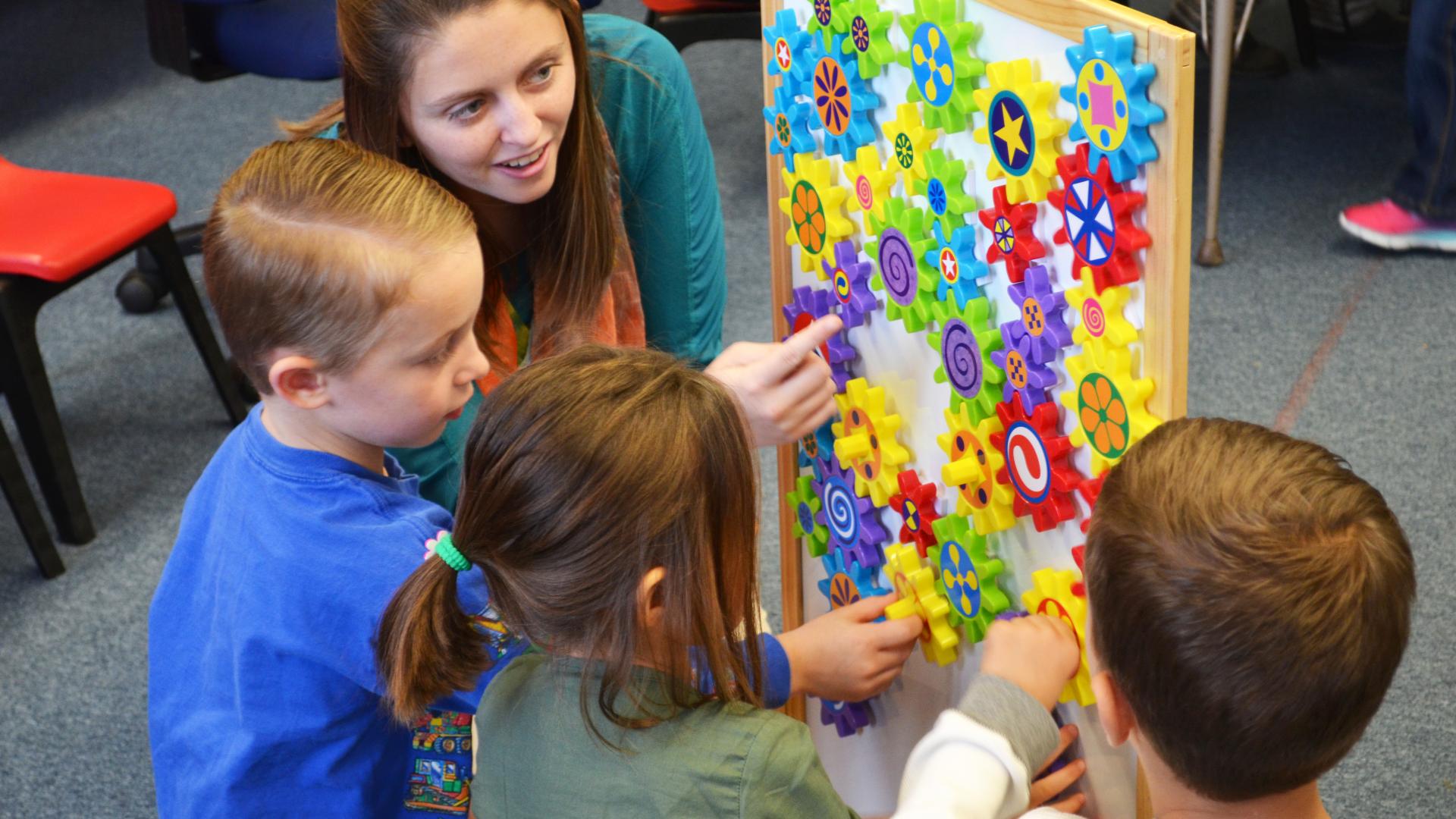 a female student teacher plays with three children