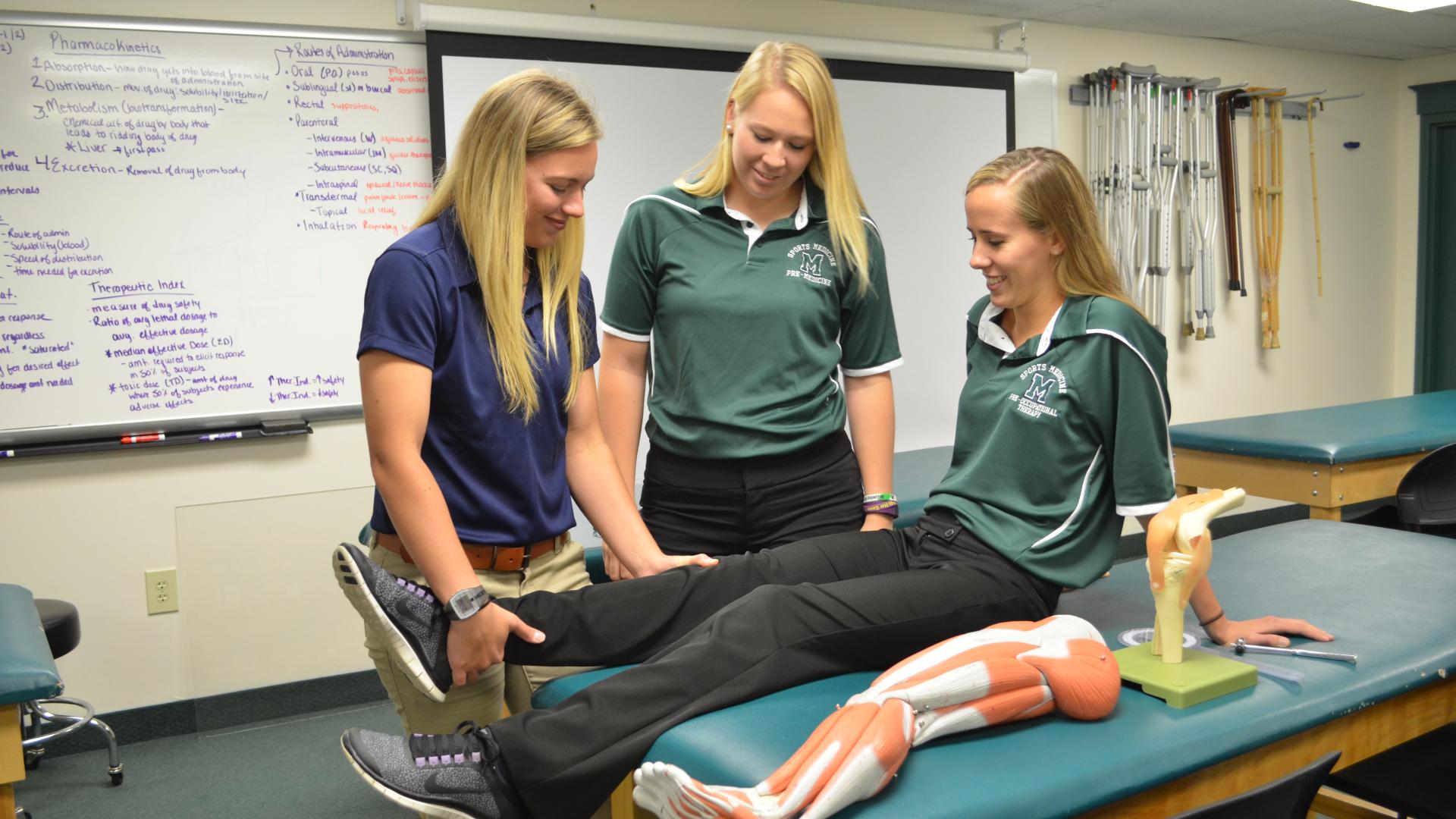 two female students exam other female student's knee