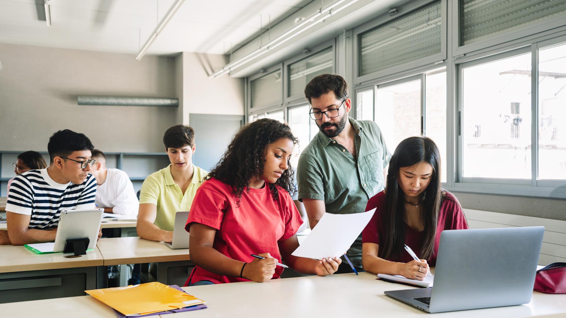 a male professor helps a class of high school students