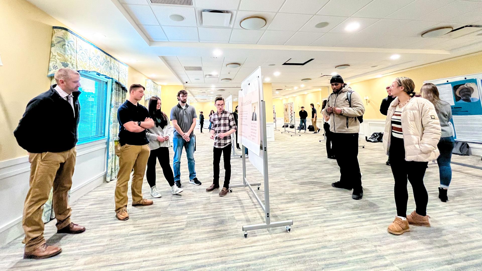 college students and professors gather for poster presentations in a large room