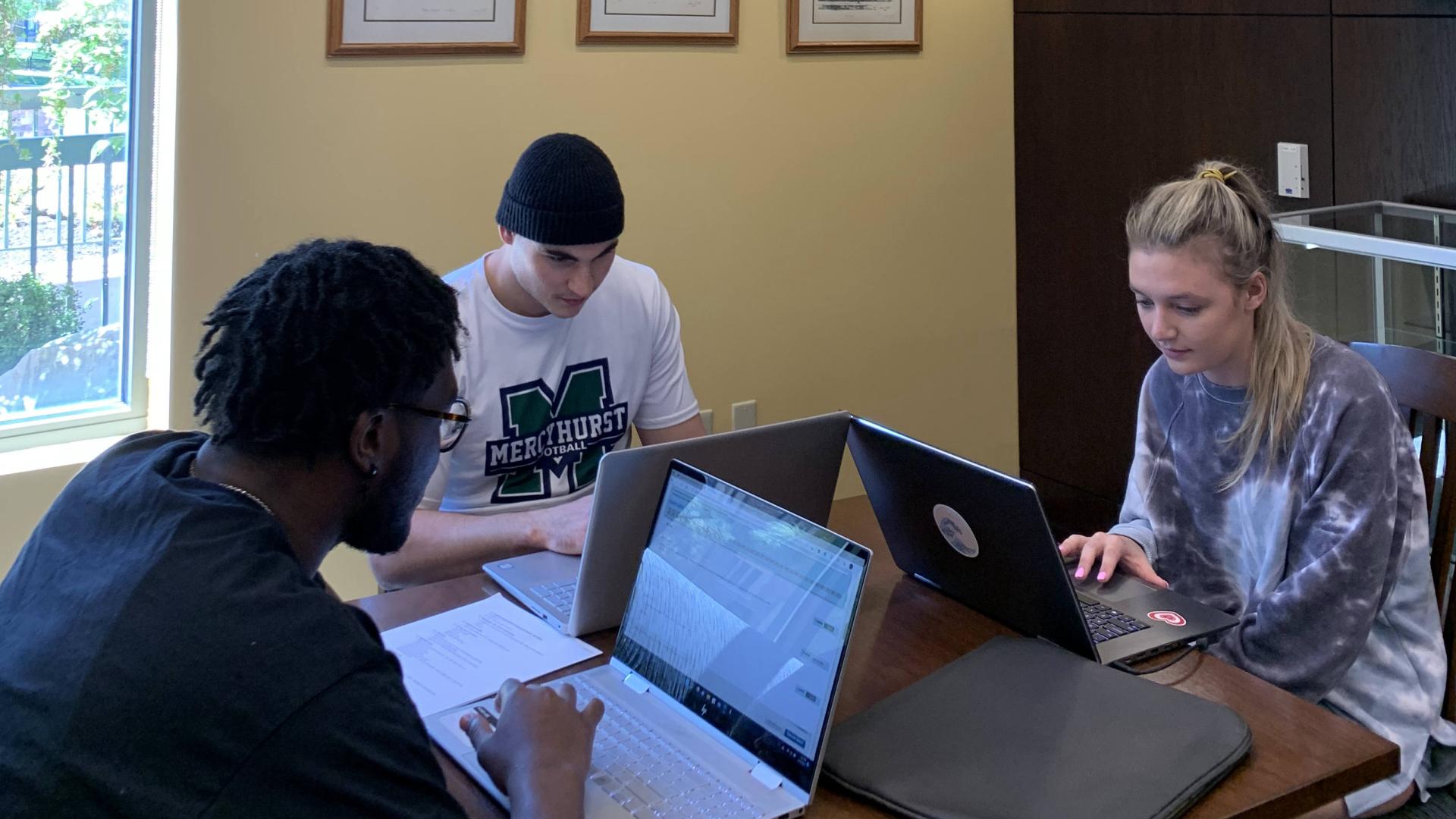 Three students working on laptops