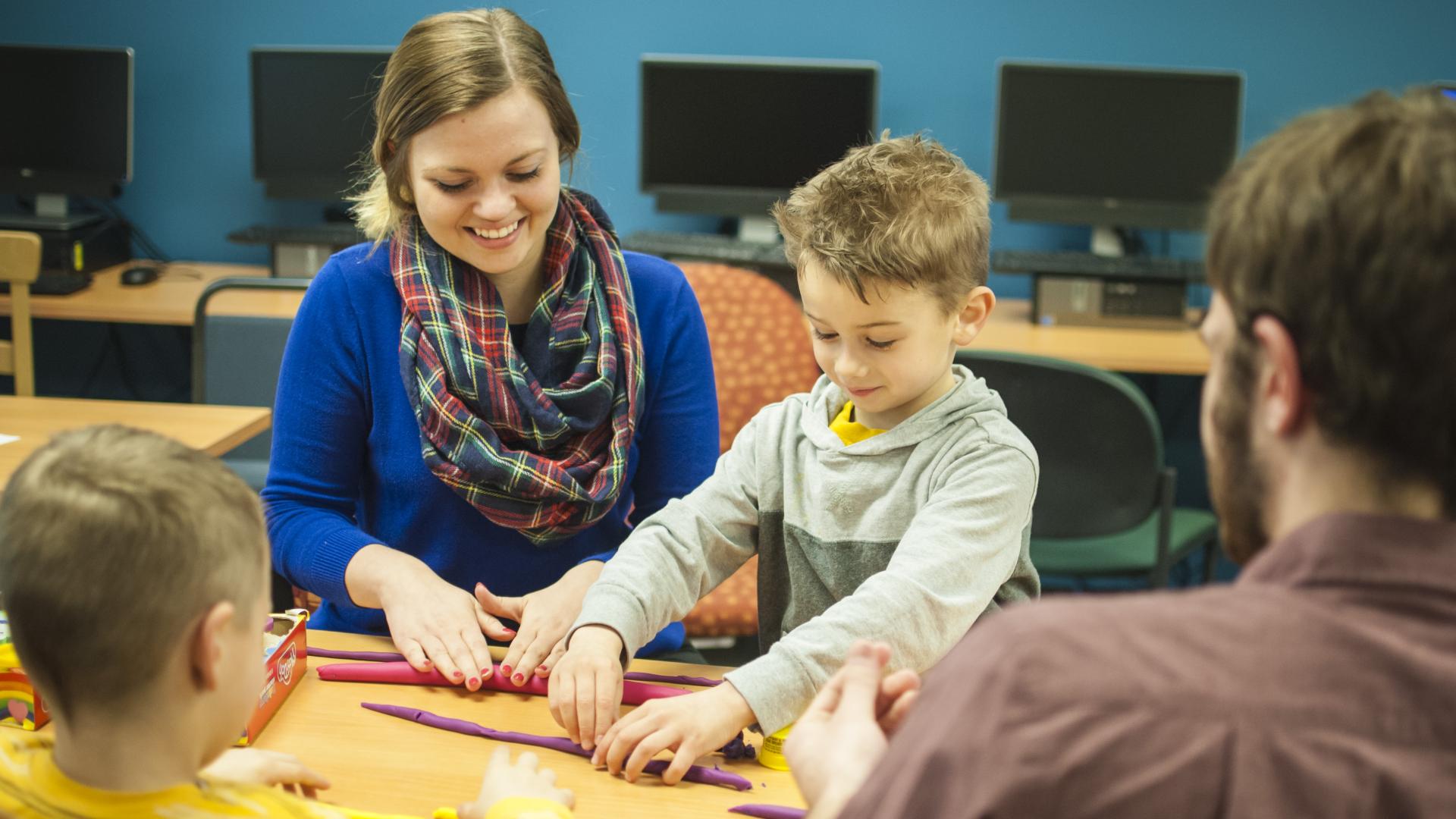 a female student works with a child in a classroom