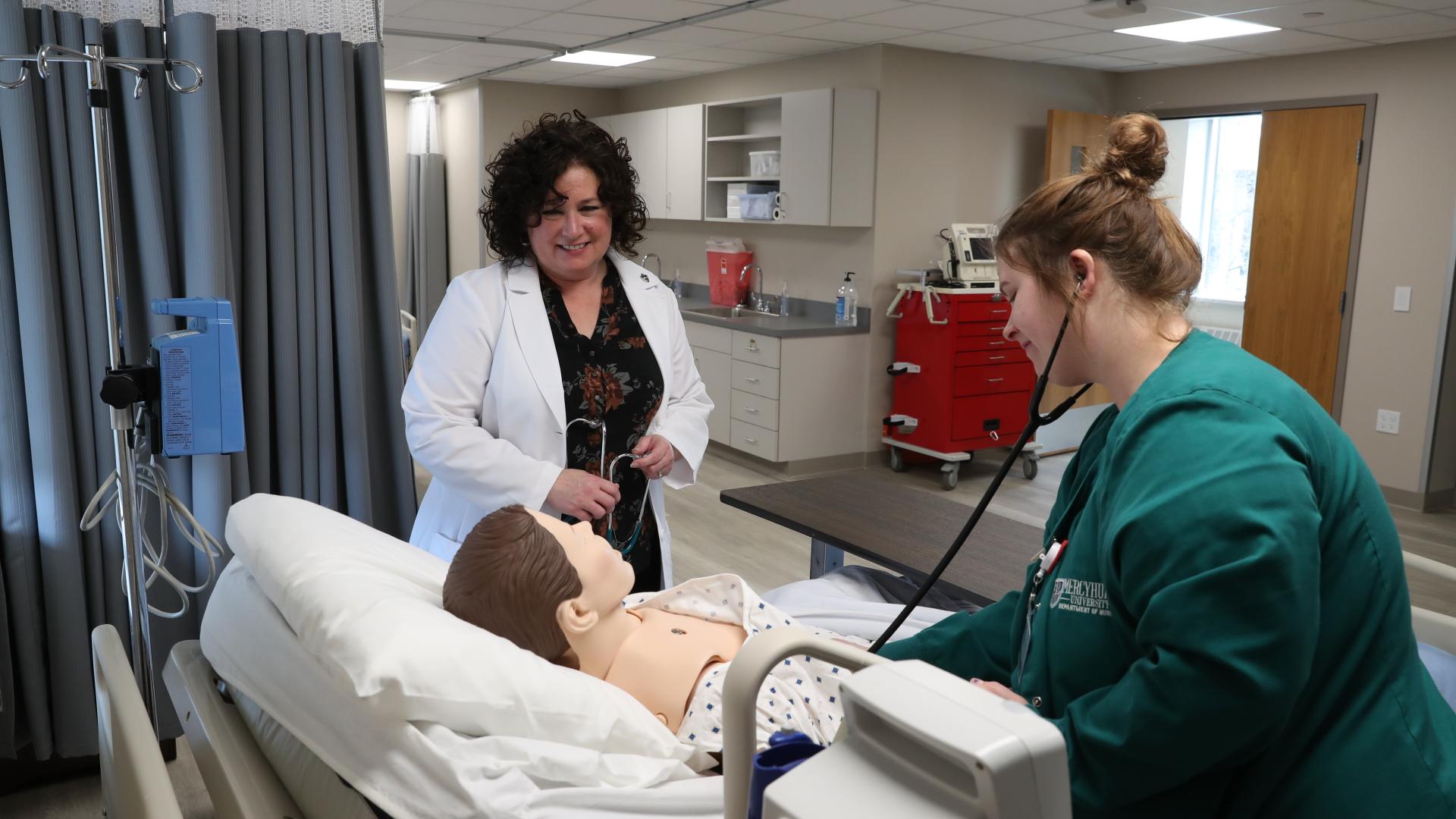 Nursing instructor and student examining mannequin