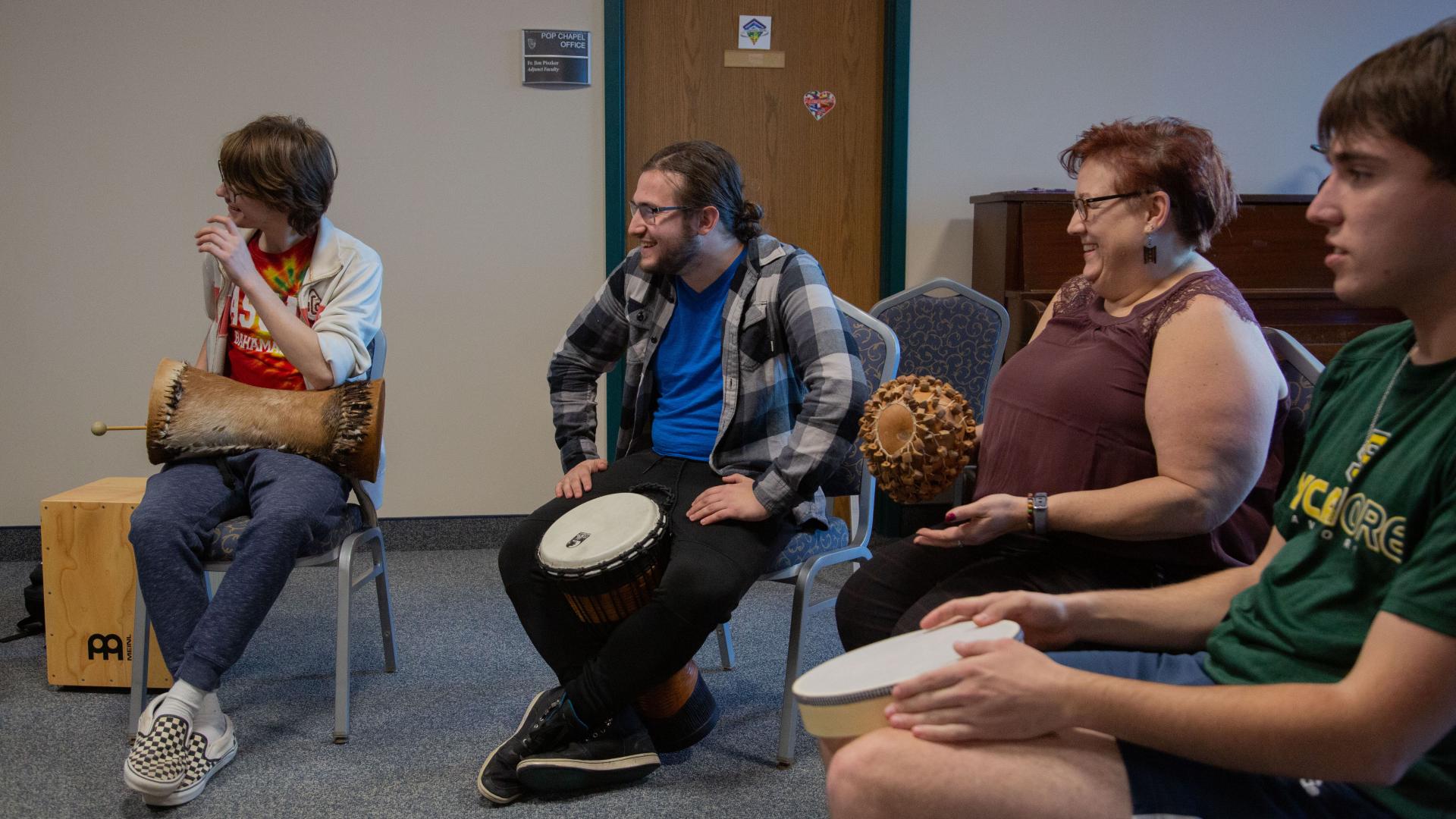 Four Music Therapy students playing percussion instruments in a classroom sitting down