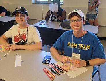 Two students pose for photo while working on assignments