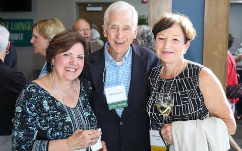 Three alumni pose at an event