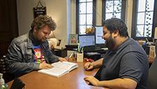 Male student and academic counselor work at a desk