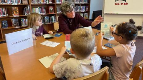 Professor Jann Haas sitting with children at a table
