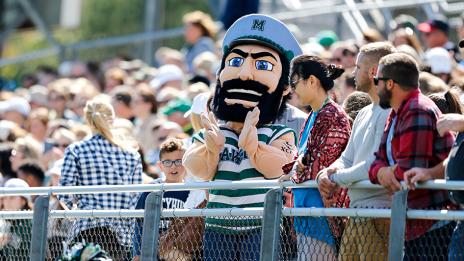 Luke the Laker mascot in the bleachers with fans at an athletics game