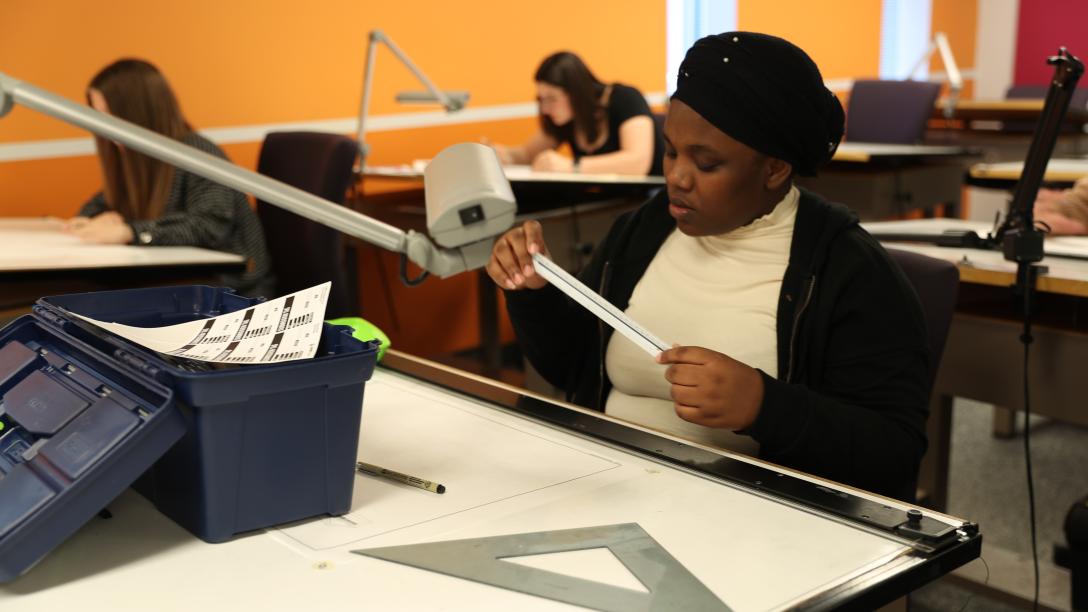 a female student measures blueprints