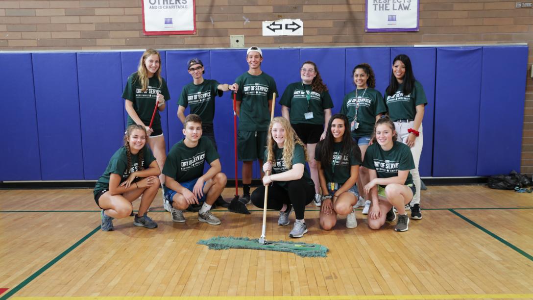 a group of students pose while cleaning a gym