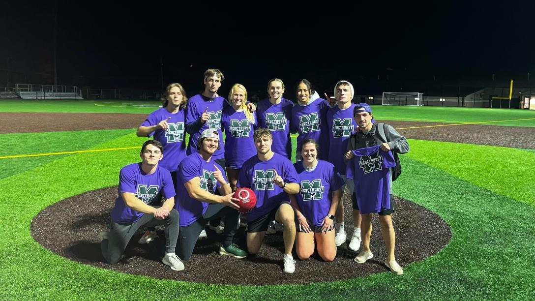 a team of students pose on the mercyhurst baseball field