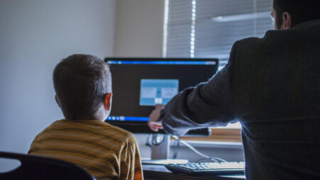 Psychology professional with patient referencing information on a computer