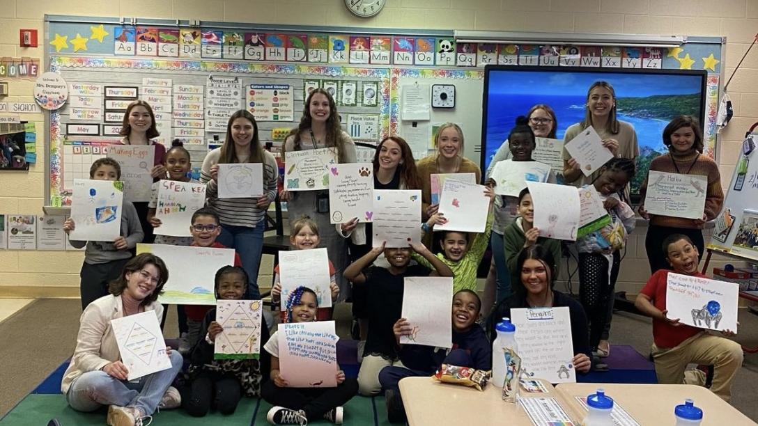 Students holding up poster presentations.