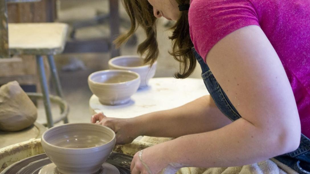 Art student spinning clay on wheel