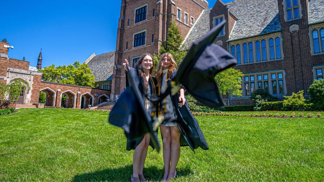 Graduation 2026 two female graduates throwing their graduation caps in front of Old Main