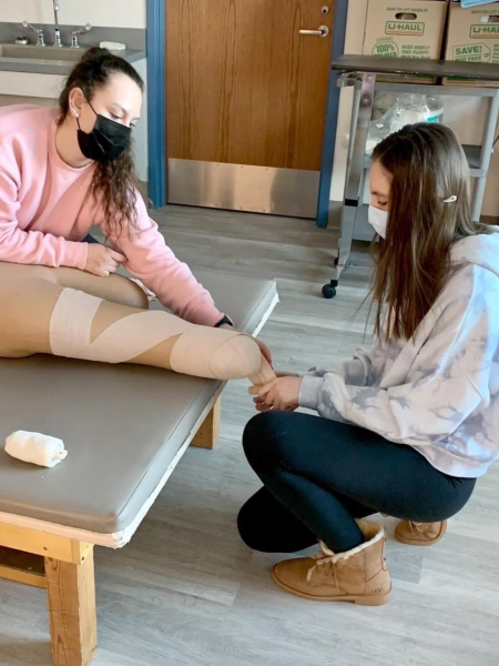 a physical therapist assistant wraps a patient's leg