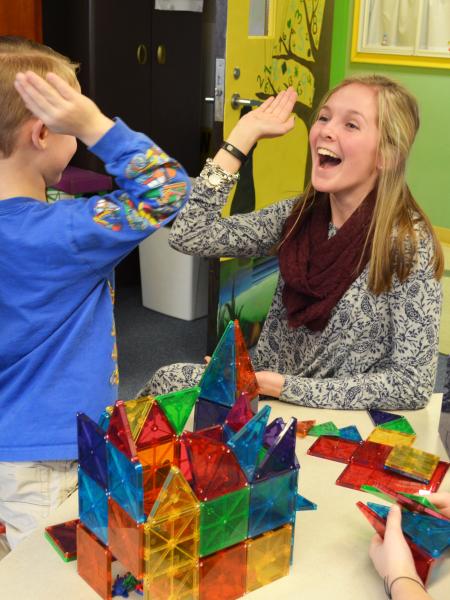 a female student teacher high-fives a child