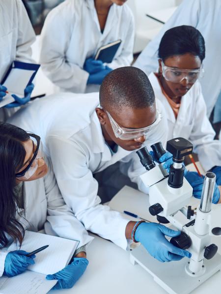 group of medical students examine microscope slide