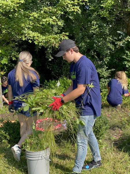 a male student cleans an outdoor garden area