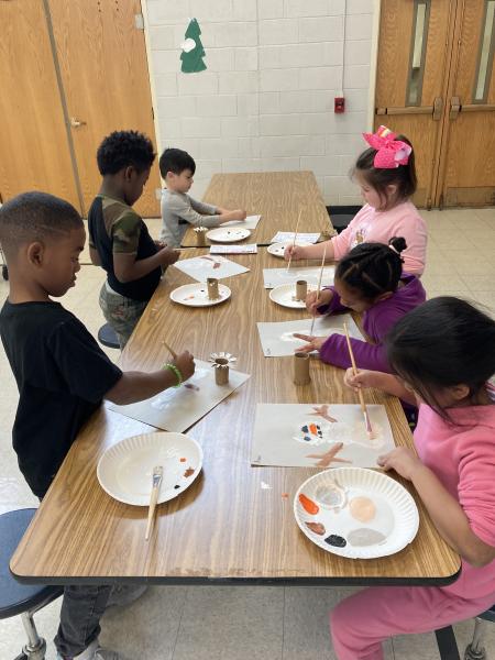 a group of children paint at a table