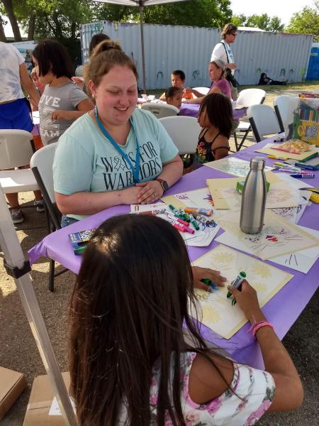 a student colors with a young girl