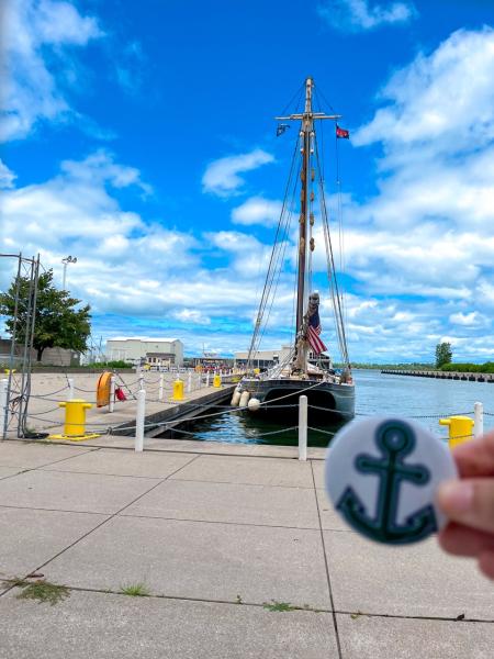 A sailboat with a Mercyhurst anchor pin in the foreground