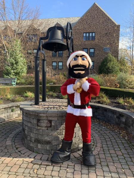 Luke dressed as Santa in front of bell