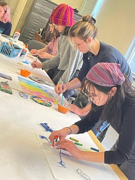 Three female art students painting in a classroom setting