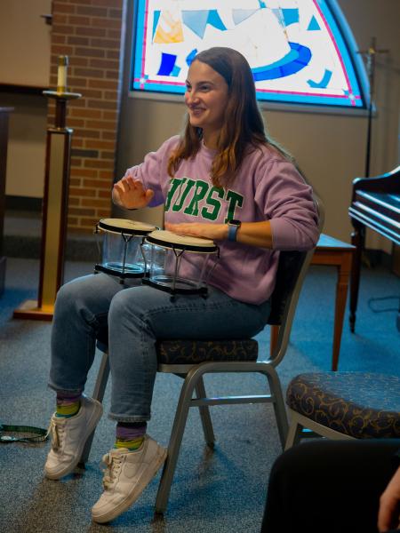 Female Music Therapy student playing percussion sitting down in a classroom setting