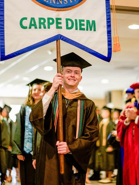 Male graduate holding Carpe Diem flag