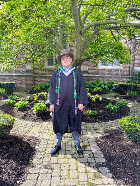 Graduation 2026 one male graduate in front of the Chapel and the magnolia tree
